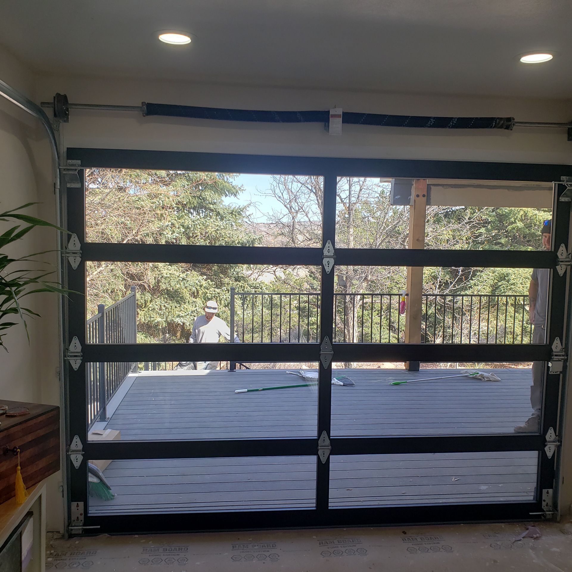 Glass garage door open to a deck with trees visible.