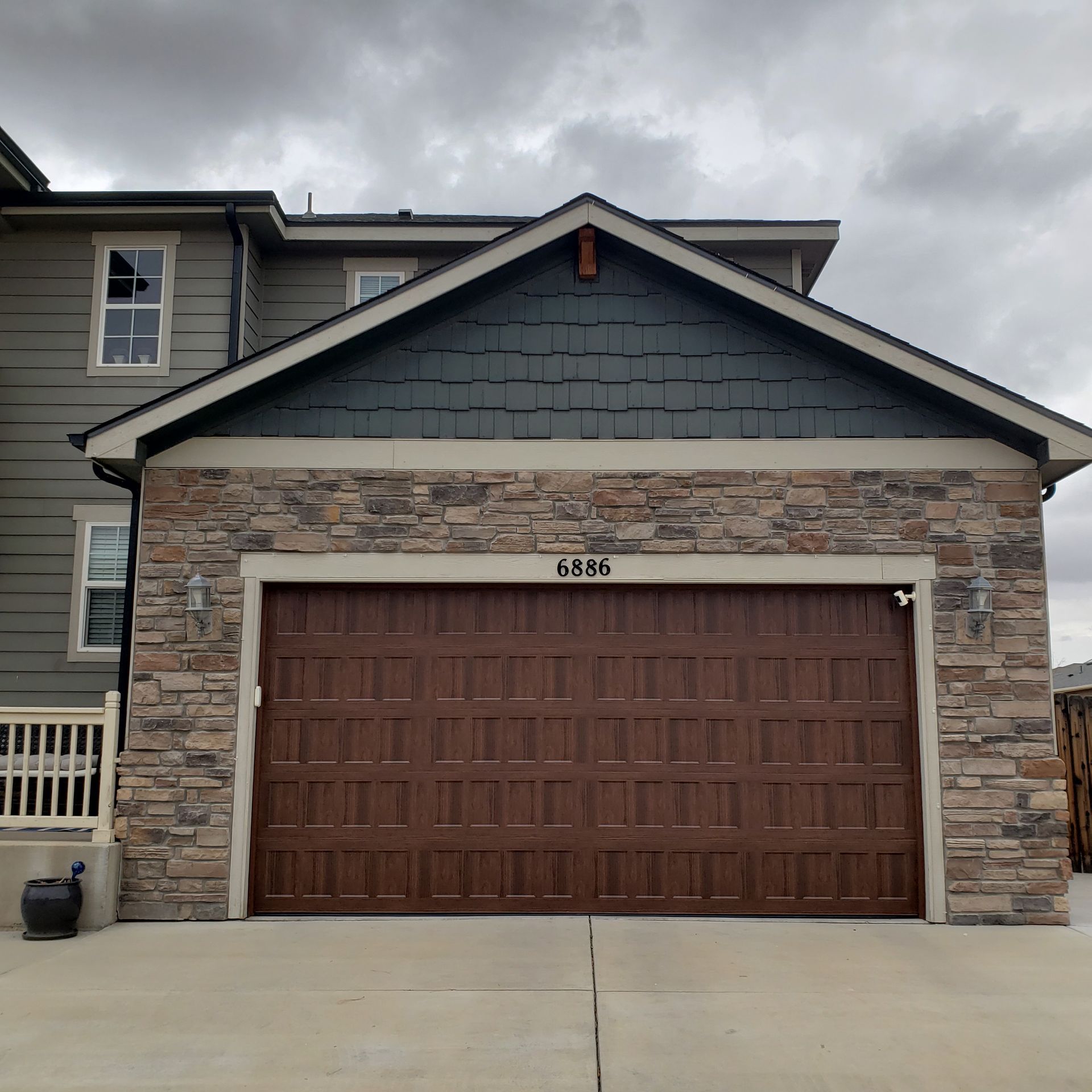 Brown garage door on a house with stone accents, gray sky.