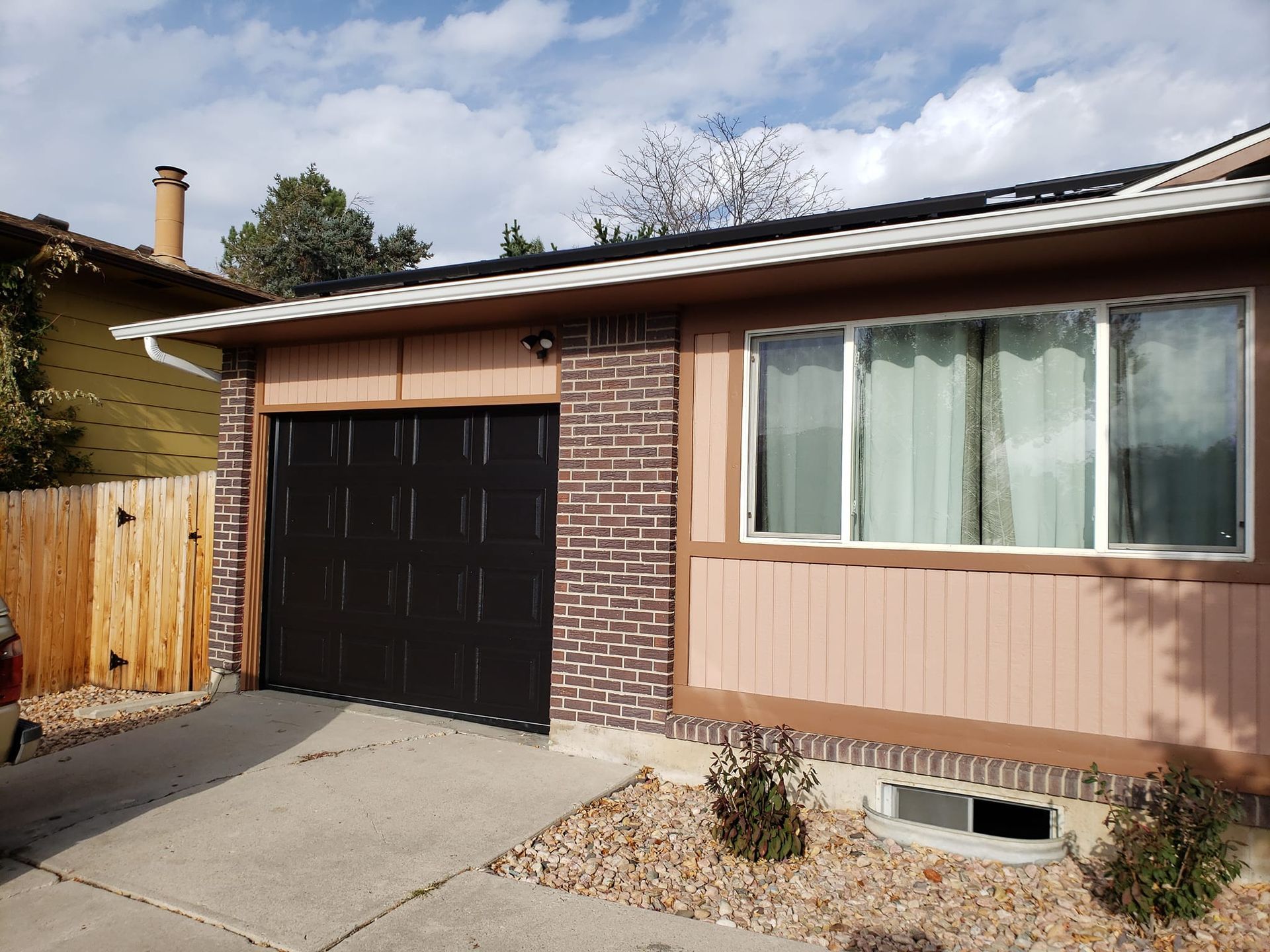 Garage and house exterior with a black garage door and brick accents.