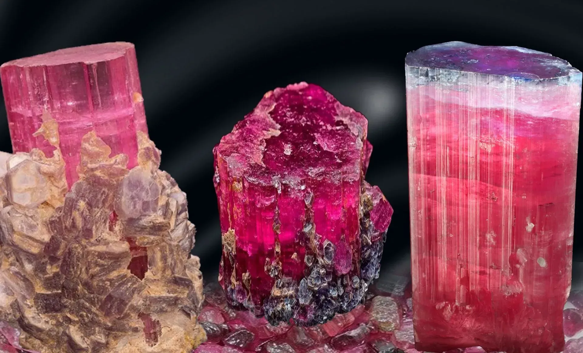 Three pink-red tourmaline crystals on dark background, including one tall faceted crystal and two rough specimens