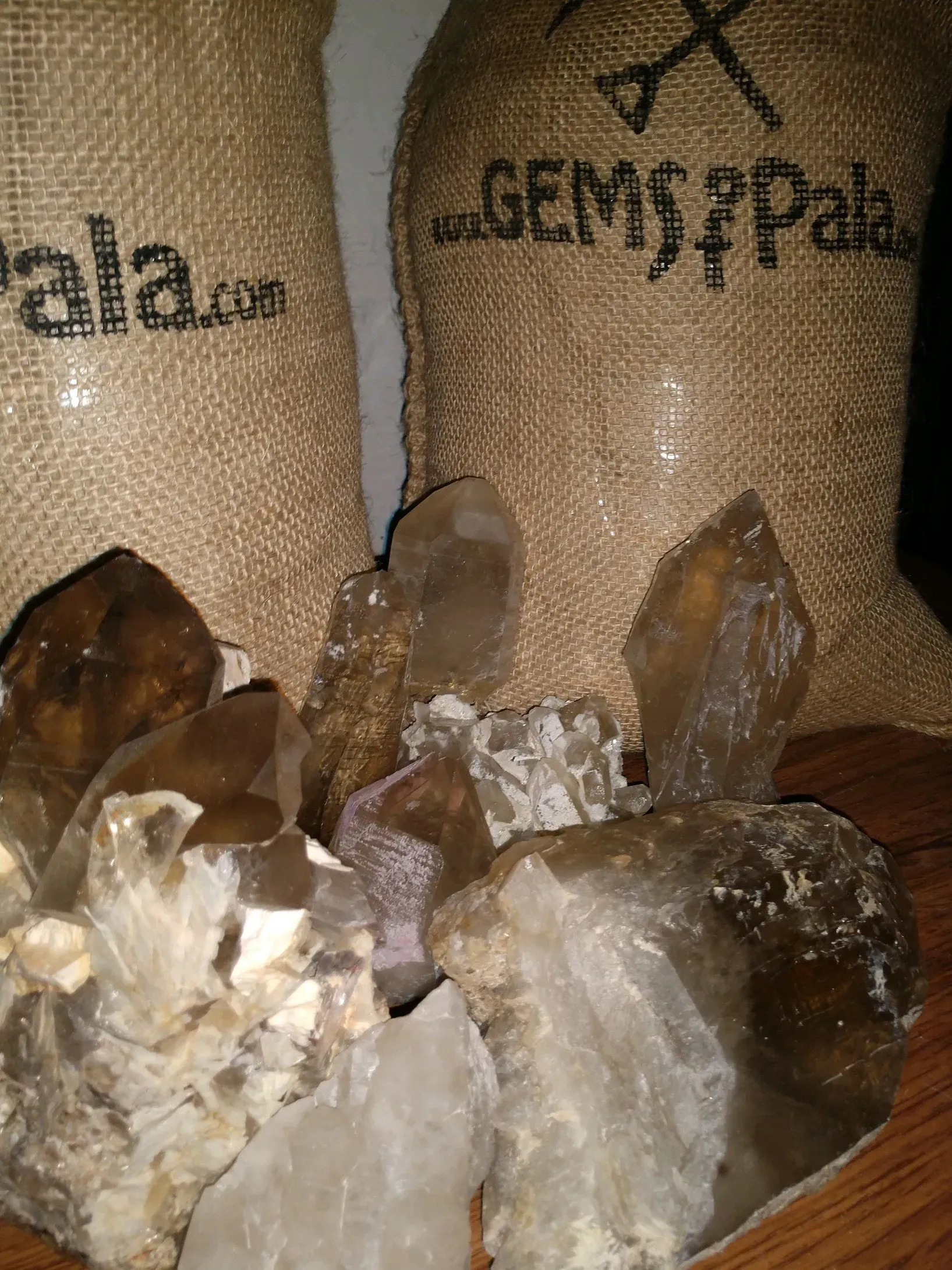 Crystals and quartz clusters displayed in front of burlap sacks labeled with gemstone names