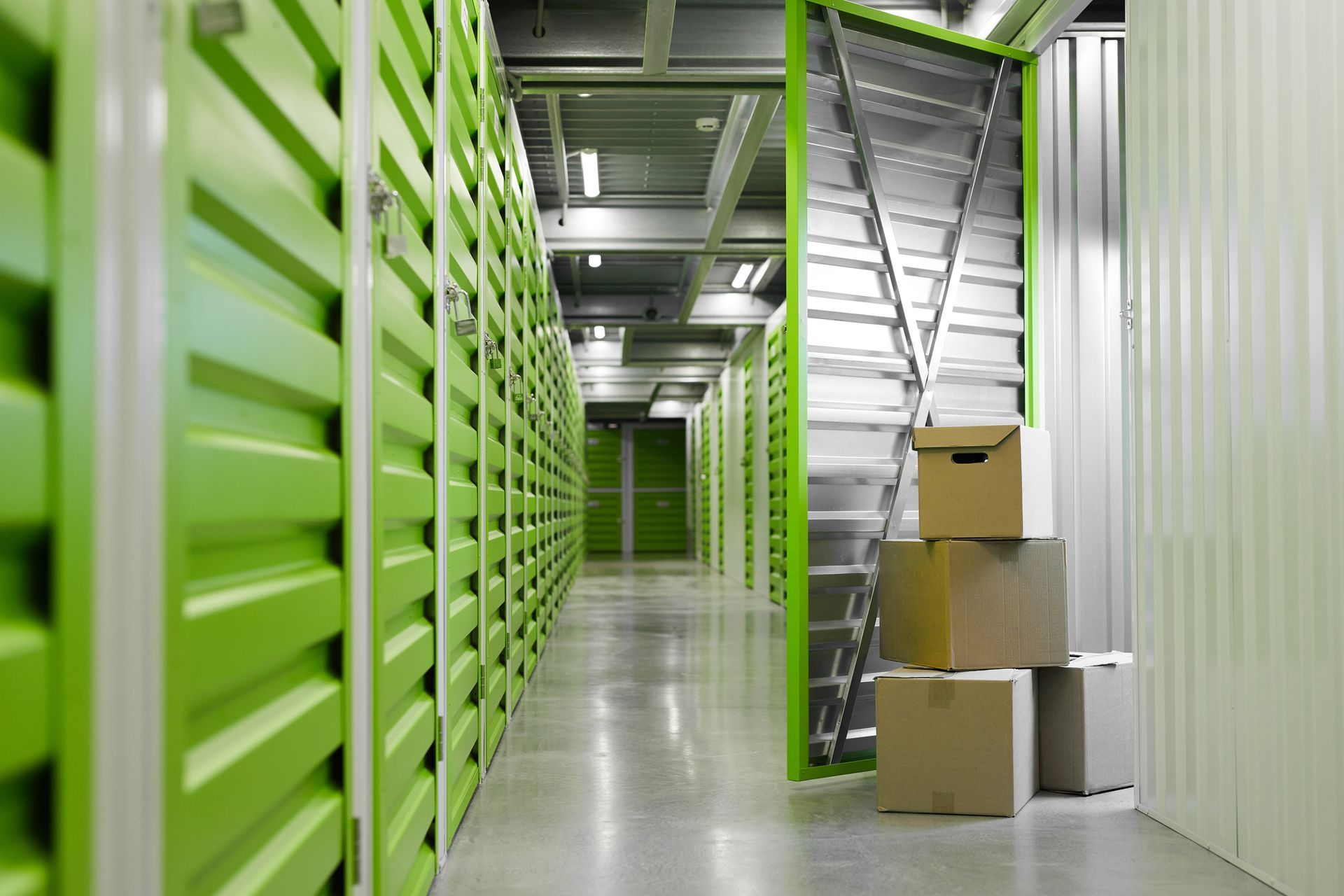 Storage unit hallway with green doors and cardboard boxes.