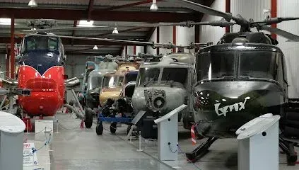 Helicopters on display in a hangar, various colors and styles.