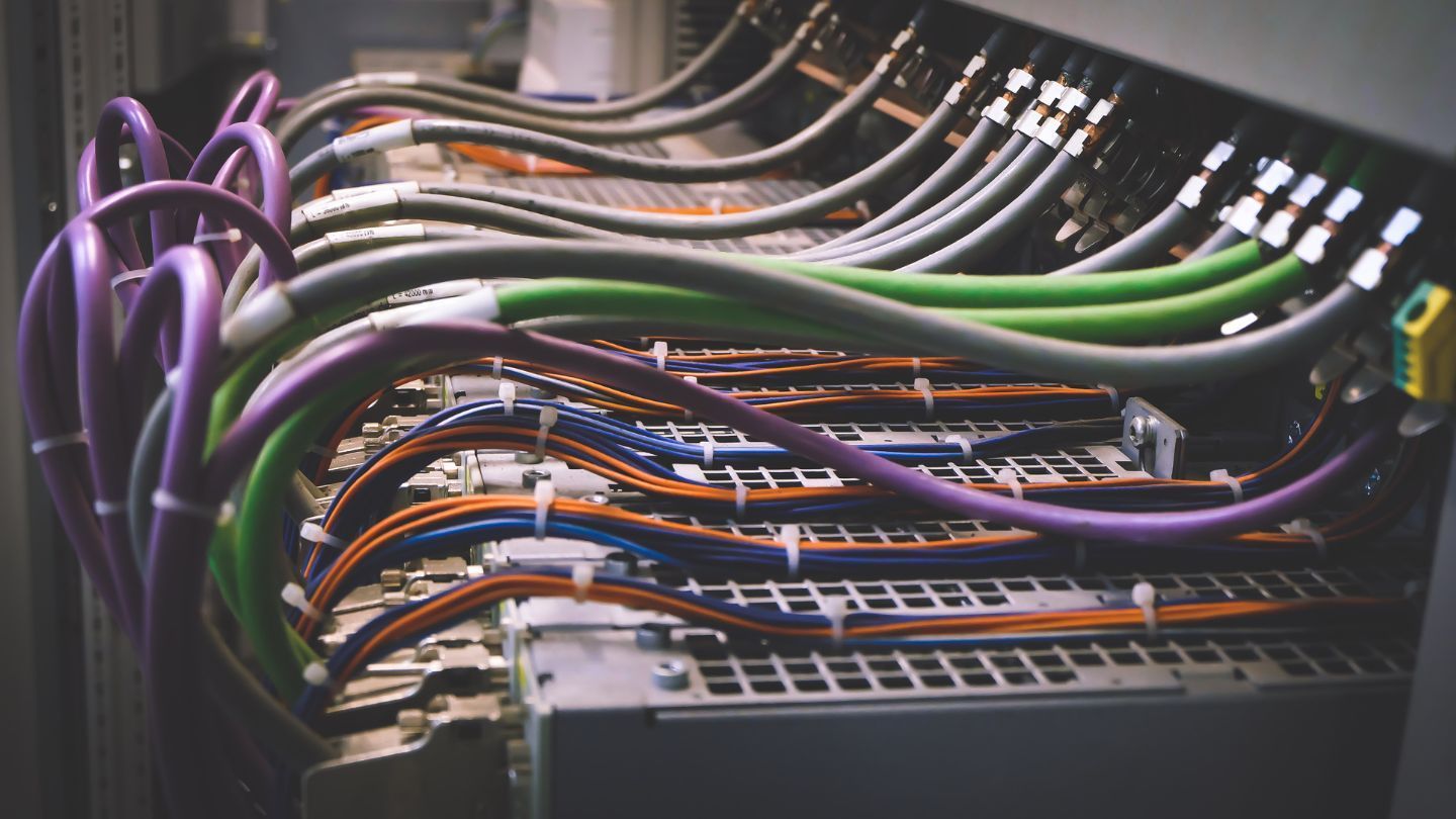 Roofer nailing shingles onto a roof under a bright blue sky.