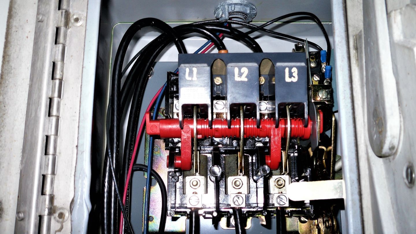 Construction worker, in orange vest and blue helmet, hammering on a rooftop.