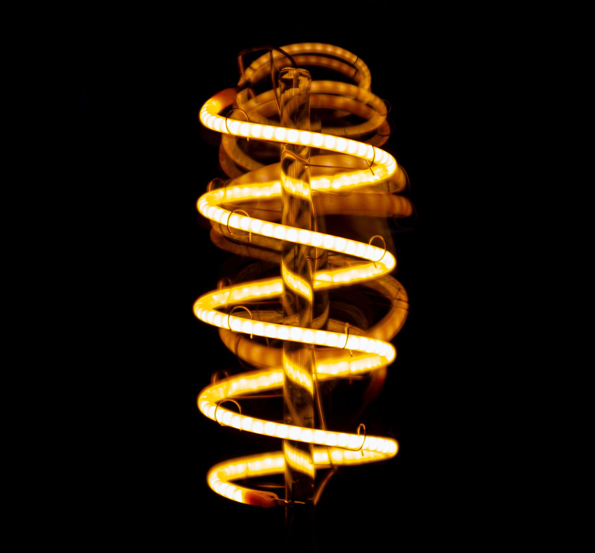 Glowing orange spiral light bulb on a black background