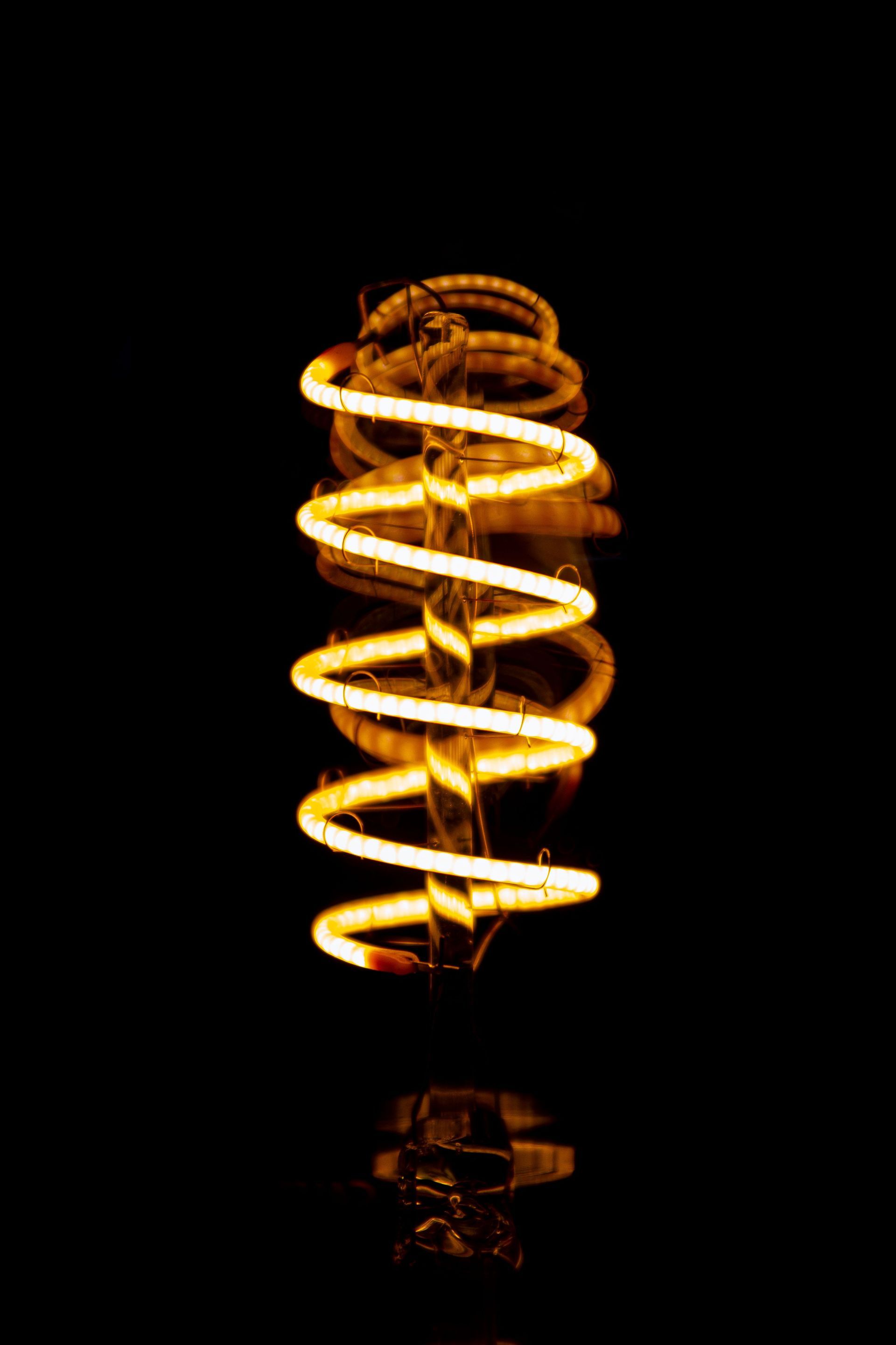 Glowing orange spiral light bulb on a black background