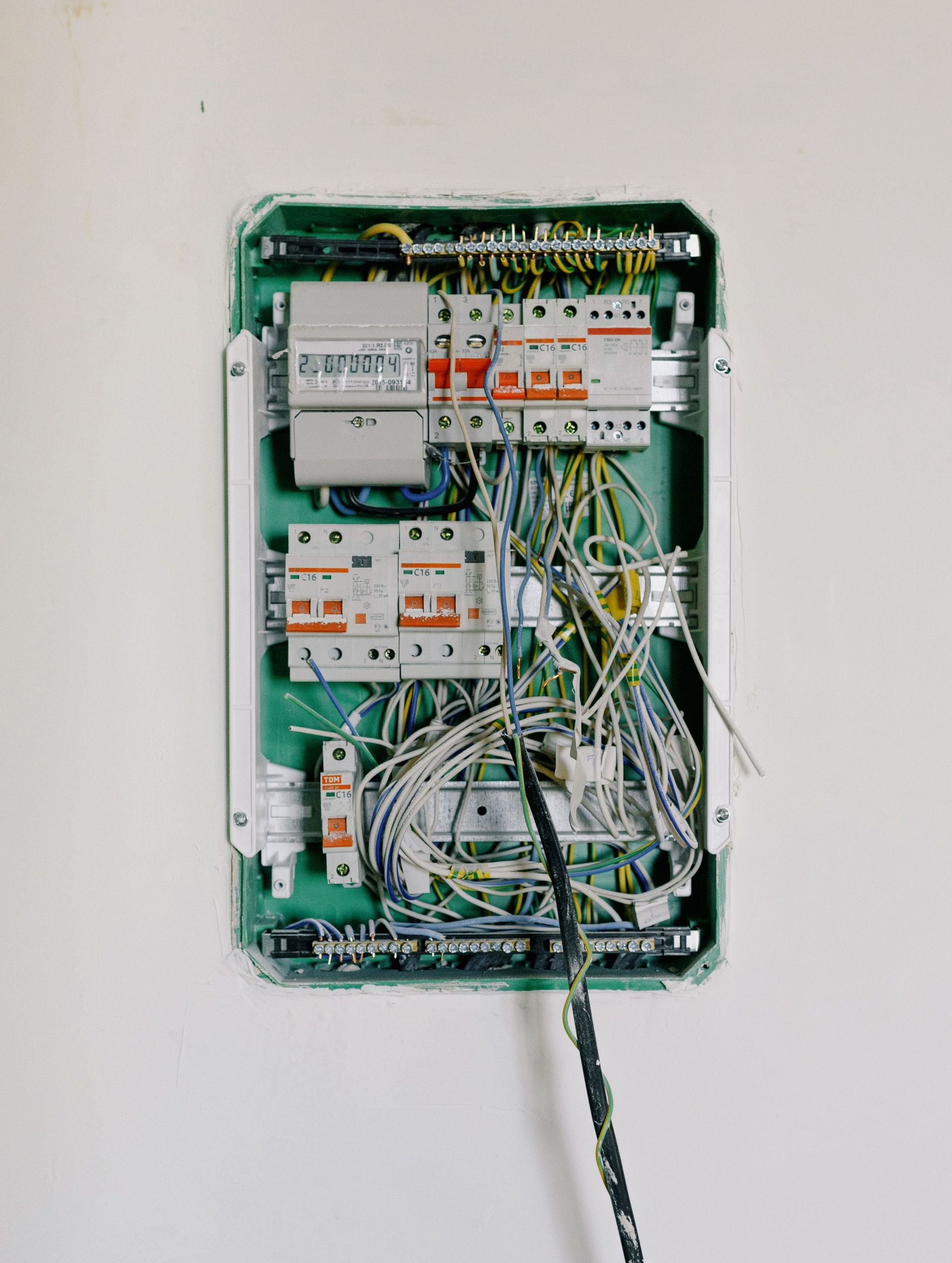 Open electrical breaker panel with tangled wires and exposed circuit breakers in a wall-mounted box