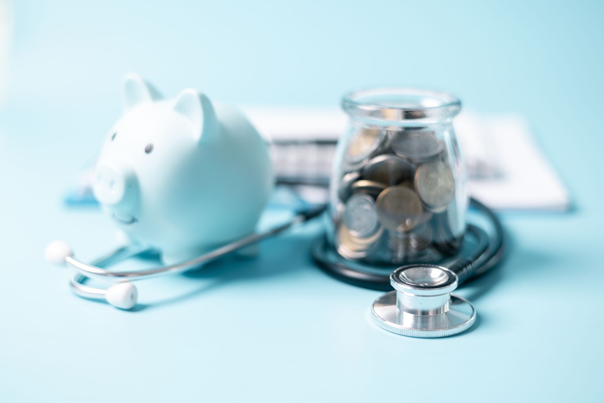 A piggy bank , stethoscope , and jar of coins on a blue background.