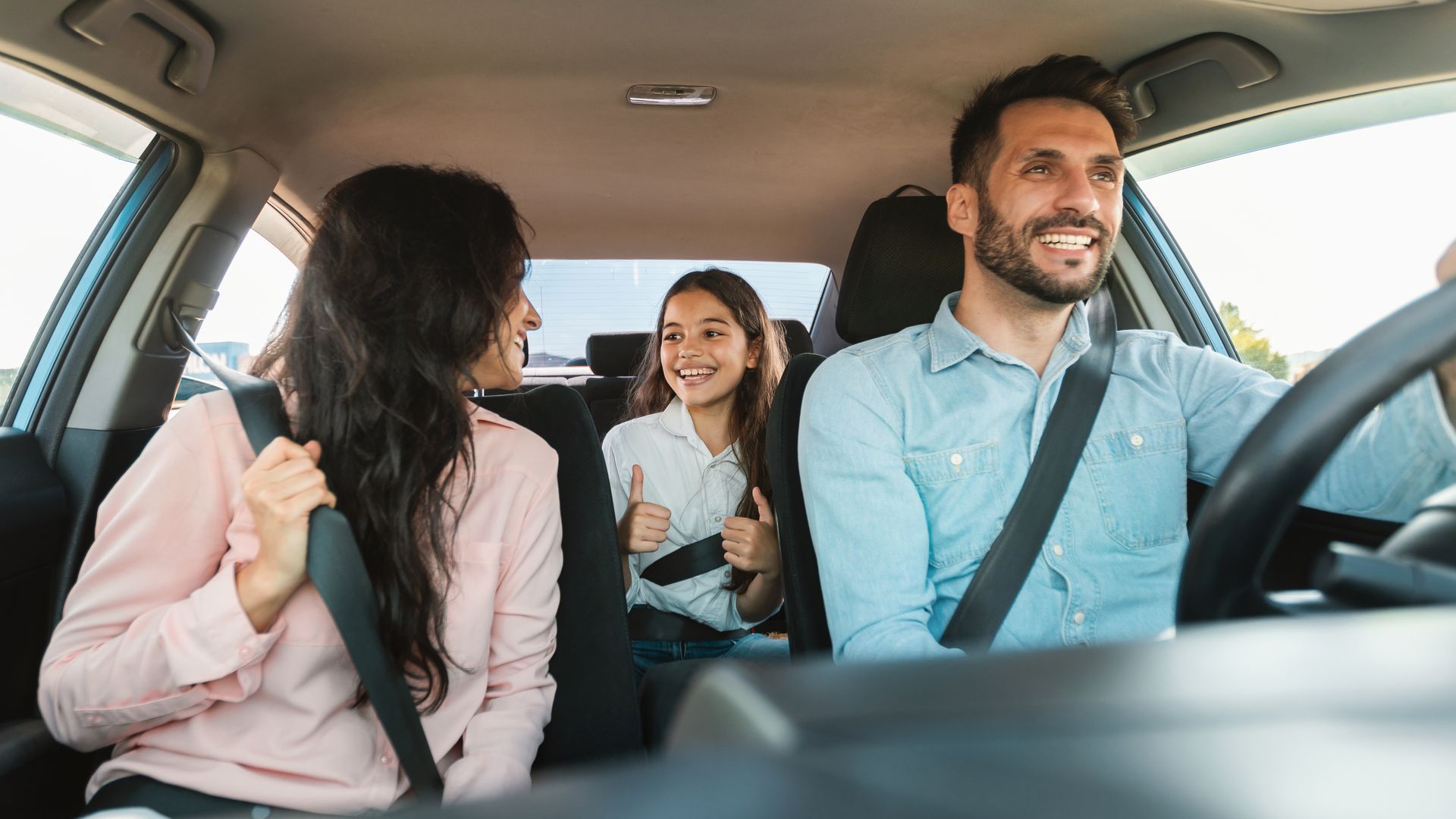 A family is sitting in the back seat of a car.