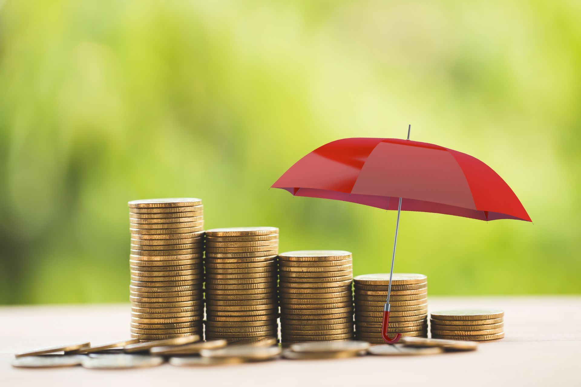 A red umbrella is sitting on top of a pile of coins.