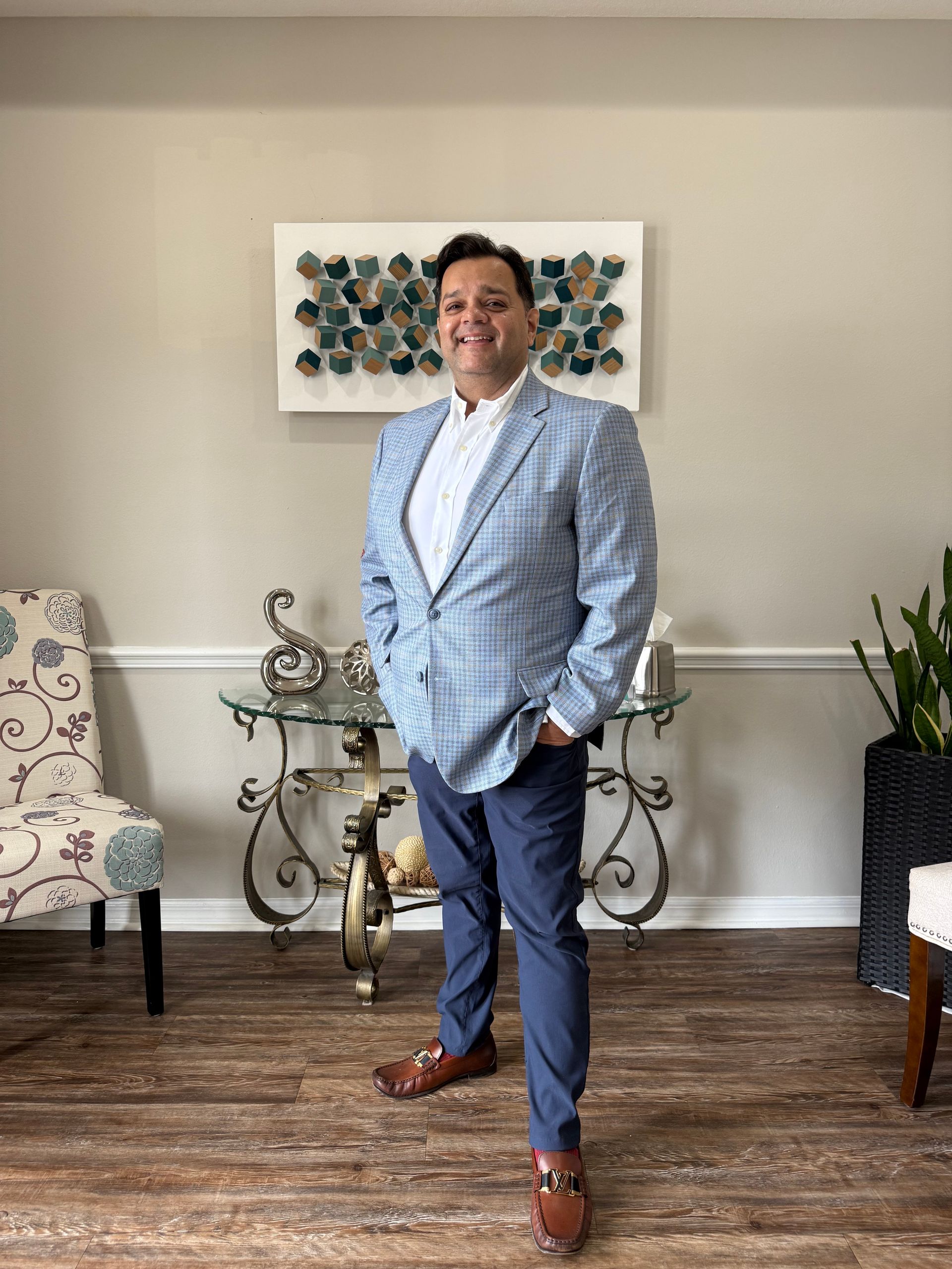 Man in a dark suit, white shirt, and blue tie, looking towards the viewer.
