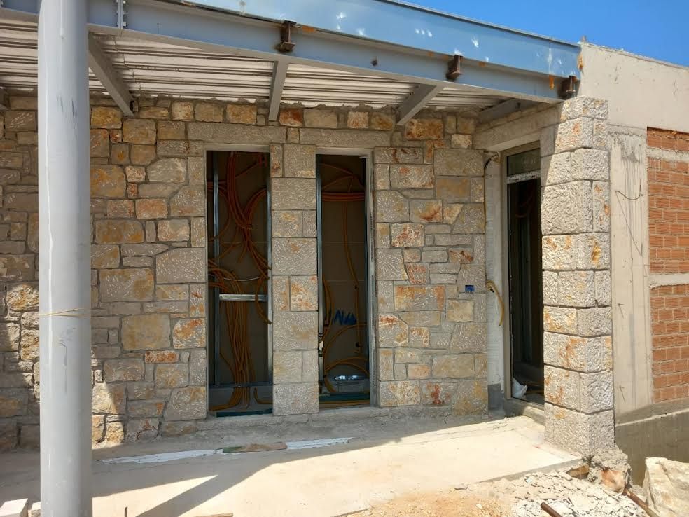A stone building under construction with a metal roof