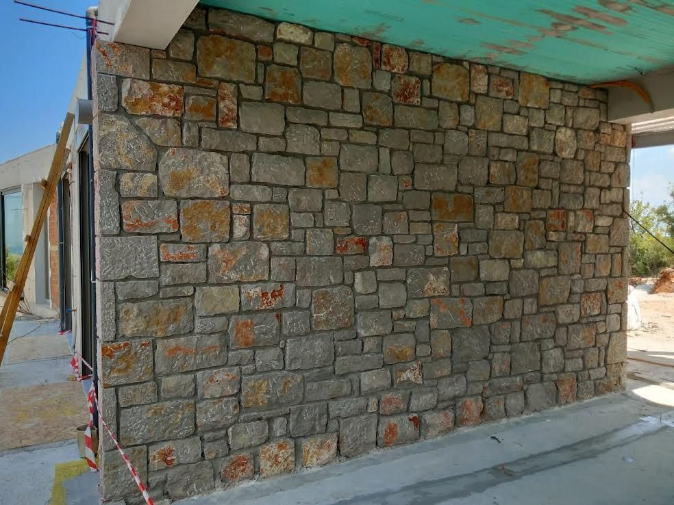 A stone wall is being built on the side of a building