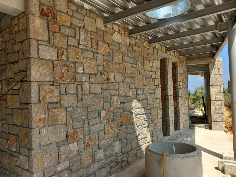 A stone wall with a metal roof is under construction.