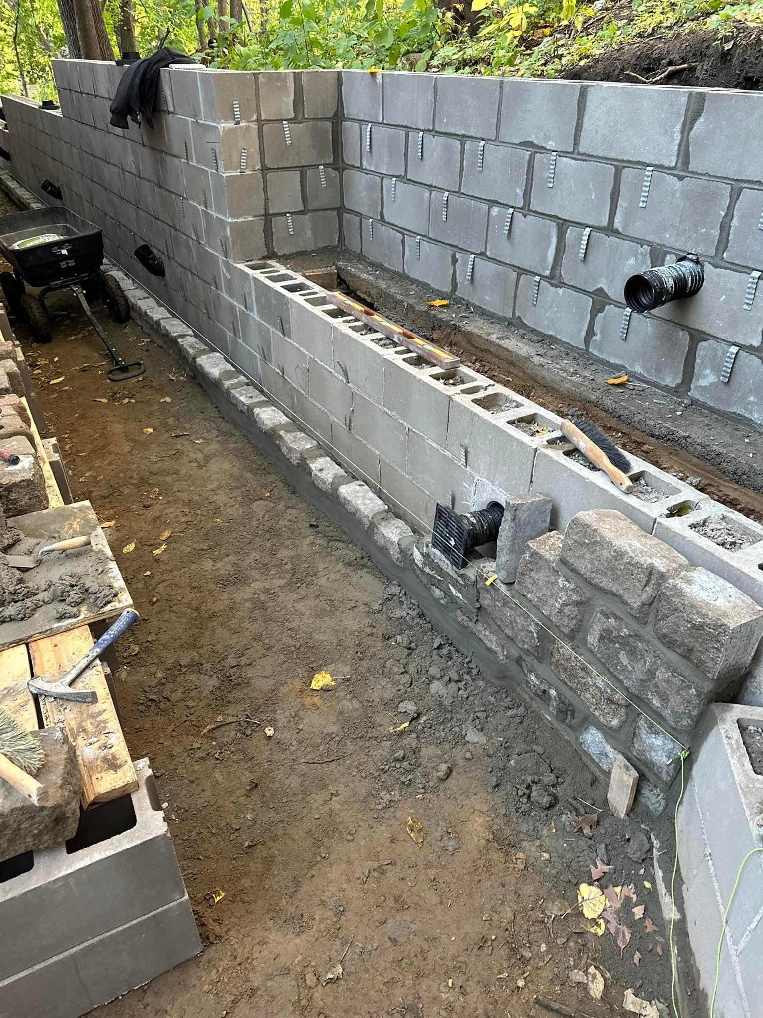 A brick wall is being built in a dirt area.
