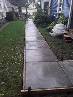A concrete walkway is being built in front of a blue house.
