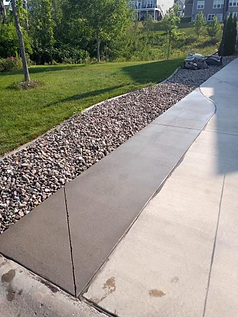 A concrete walkway with a gravel border and a grassy area in the background.