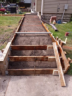 A concrete walkway is being built in front of a house.