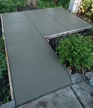 A concrete walkway is being built in a garden.
