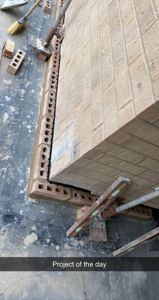 A brick wall is being built with bricks and scaffolding.