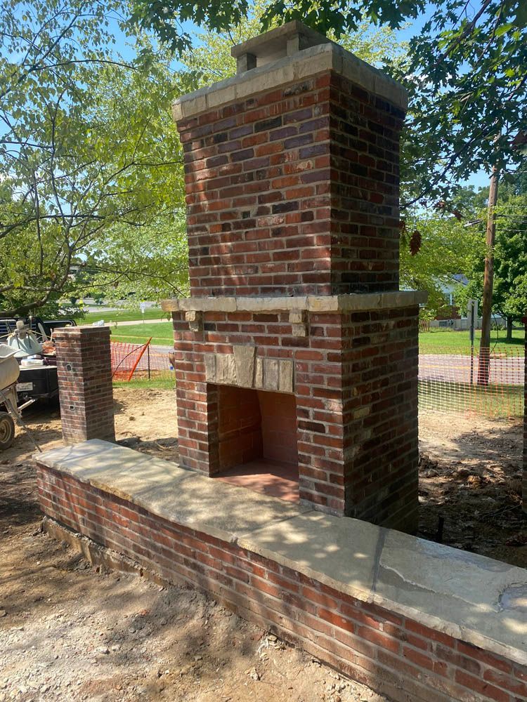 A brick fireplace is being built in the backyard of a house.