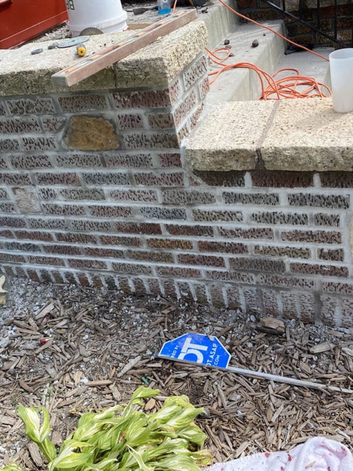 A brick wall is being built in a backyard.