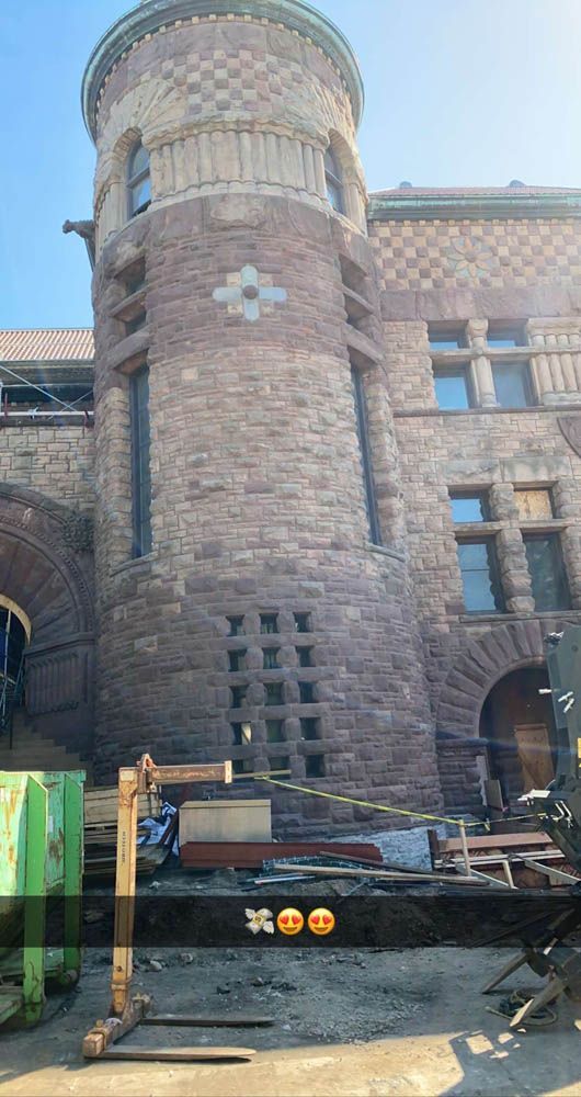 A large brick building with a tower on top of it is under construction.