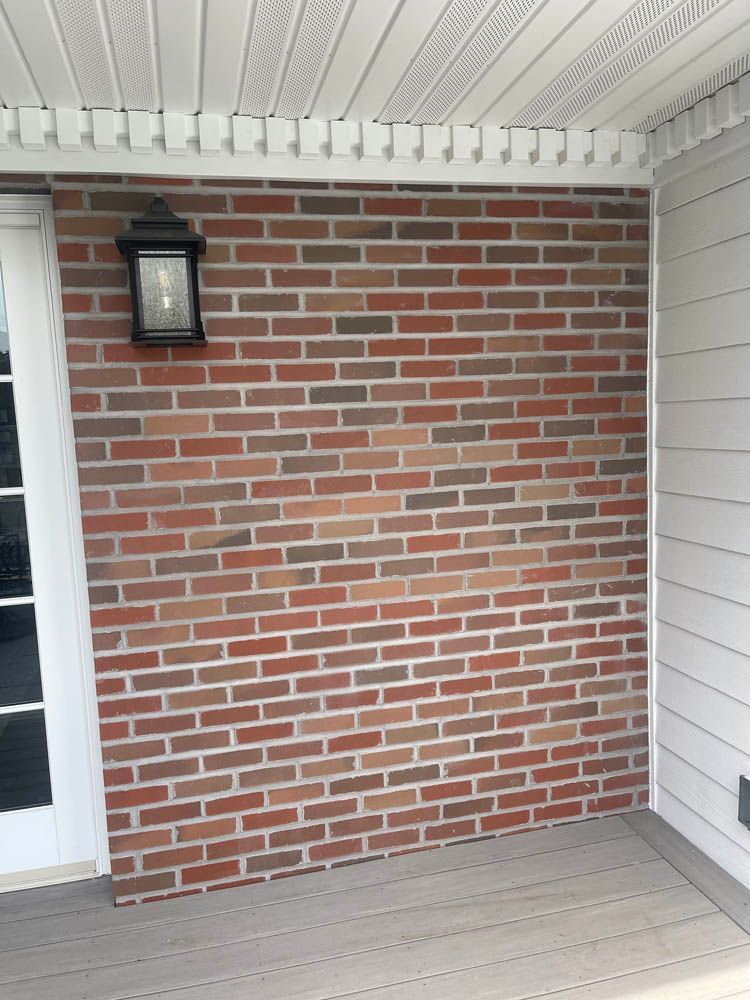 A porch with a brick wall and a light on it.