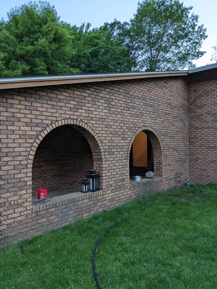 A brick building with arched windows and a hose in front of it.