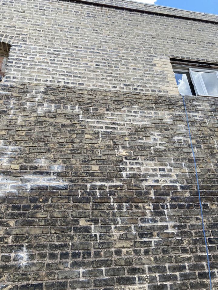 A brick wall with graffiti on it and a window.