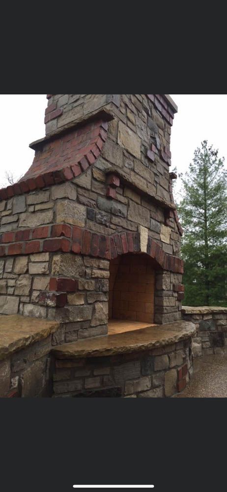 A stone fireplace with a brick surround and a wooden door.