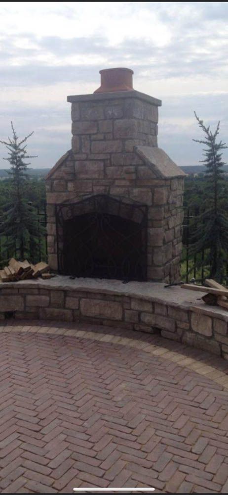 A stone fireplace is sitting on top of a brick patio.
