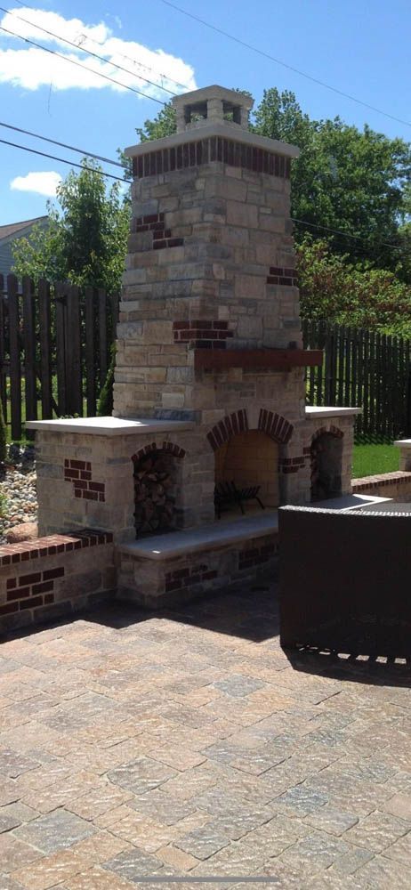 A large stone fireplace is sitting on top of a brick patio.