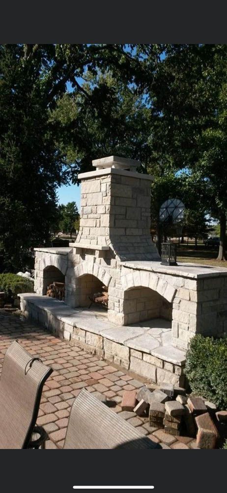 A large stone fireplace is sitting on top of a brick patio.