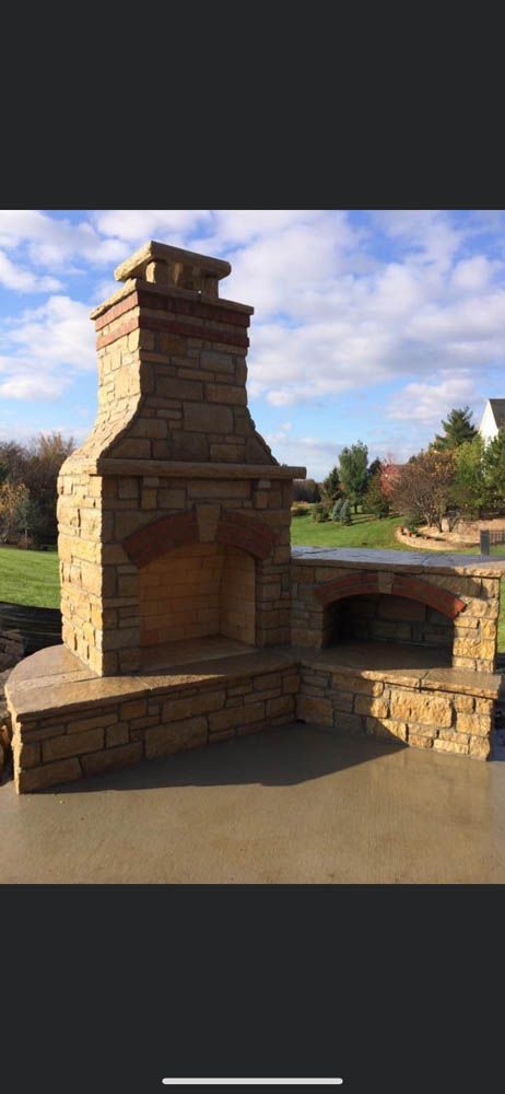 A large stone fireplace is sitting on top of a concrete patio.
