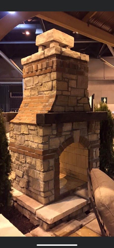 A stone fireplace is sitting in a room next to a chair.