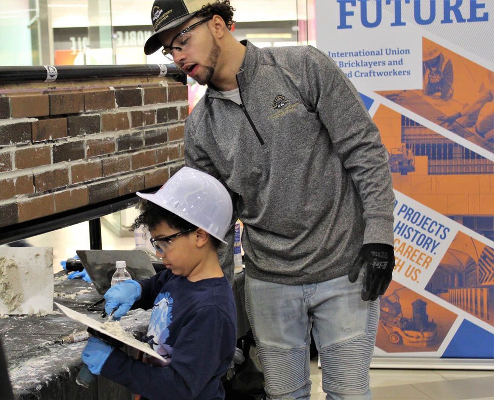 A man and a boy are working on a brick wall.