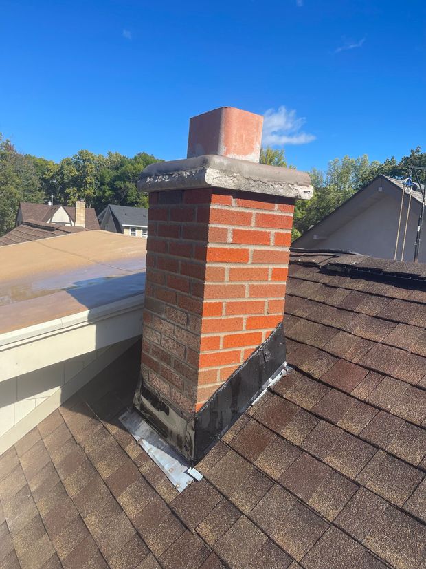 A brick chimney is sitting on top of a roof.