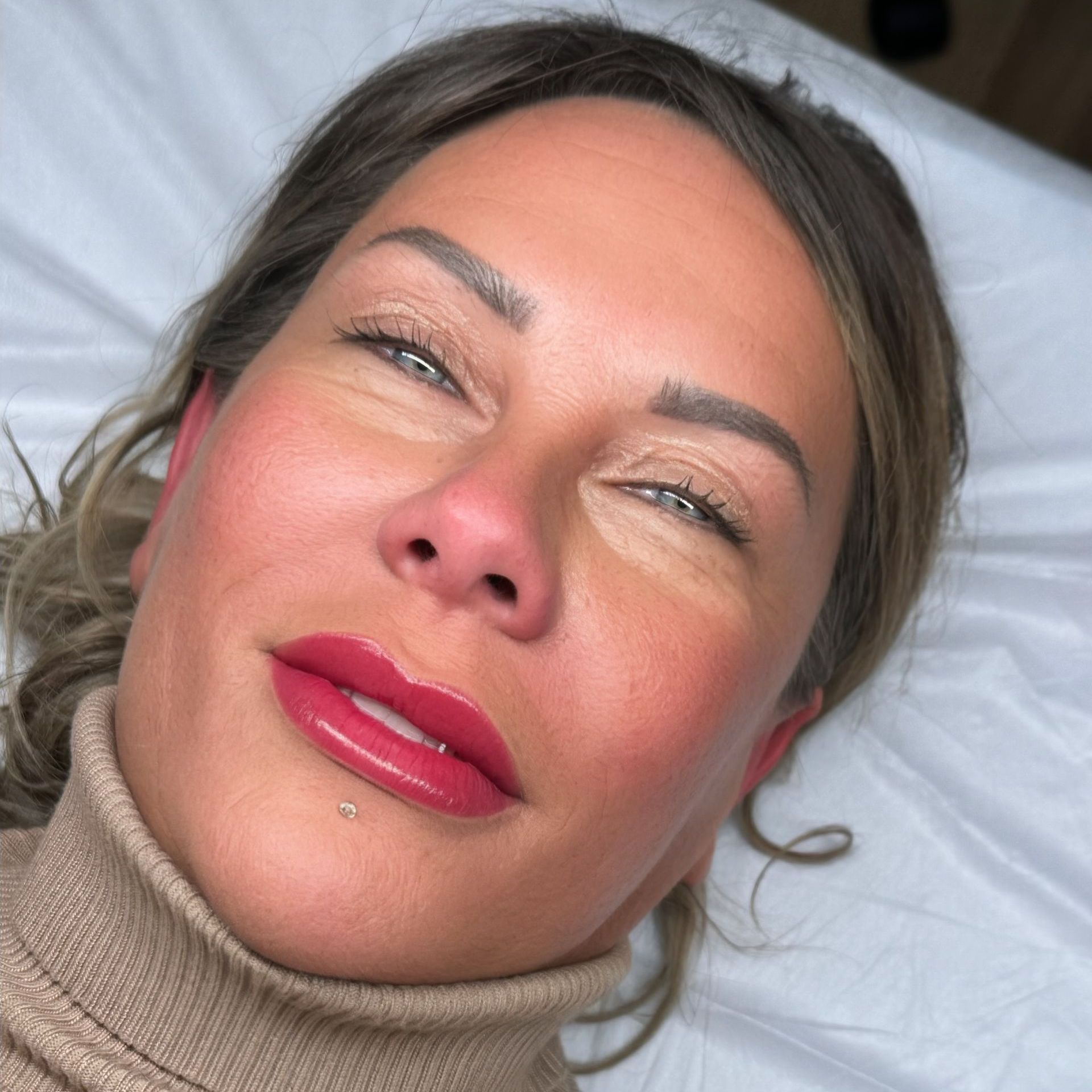 Eine Nahaufnahme des Gesichts einer Frau mit roten Lippen und einem Rollkragenpullover.