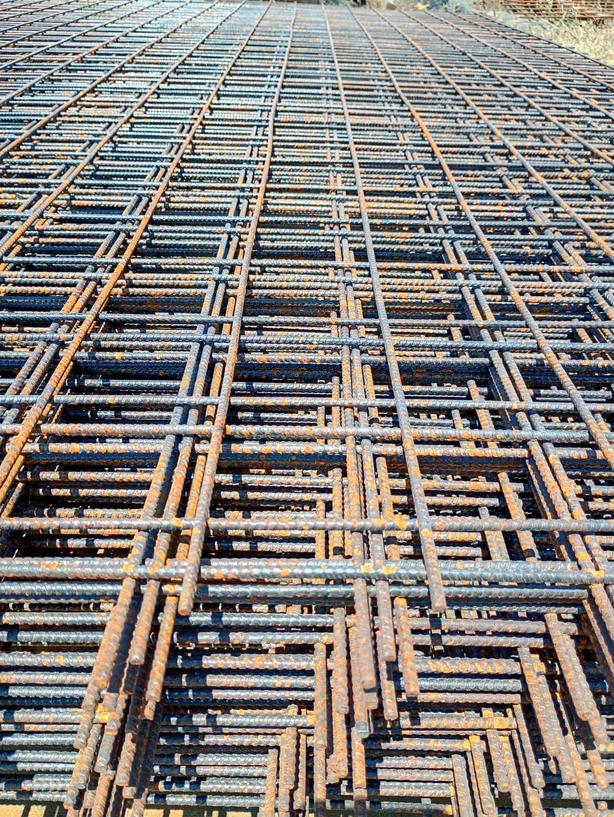 Primo piano di una rete metallica arrugginita in un cantiere edile.