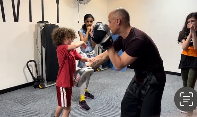 A man is teaching a young boy how to box in a gym.