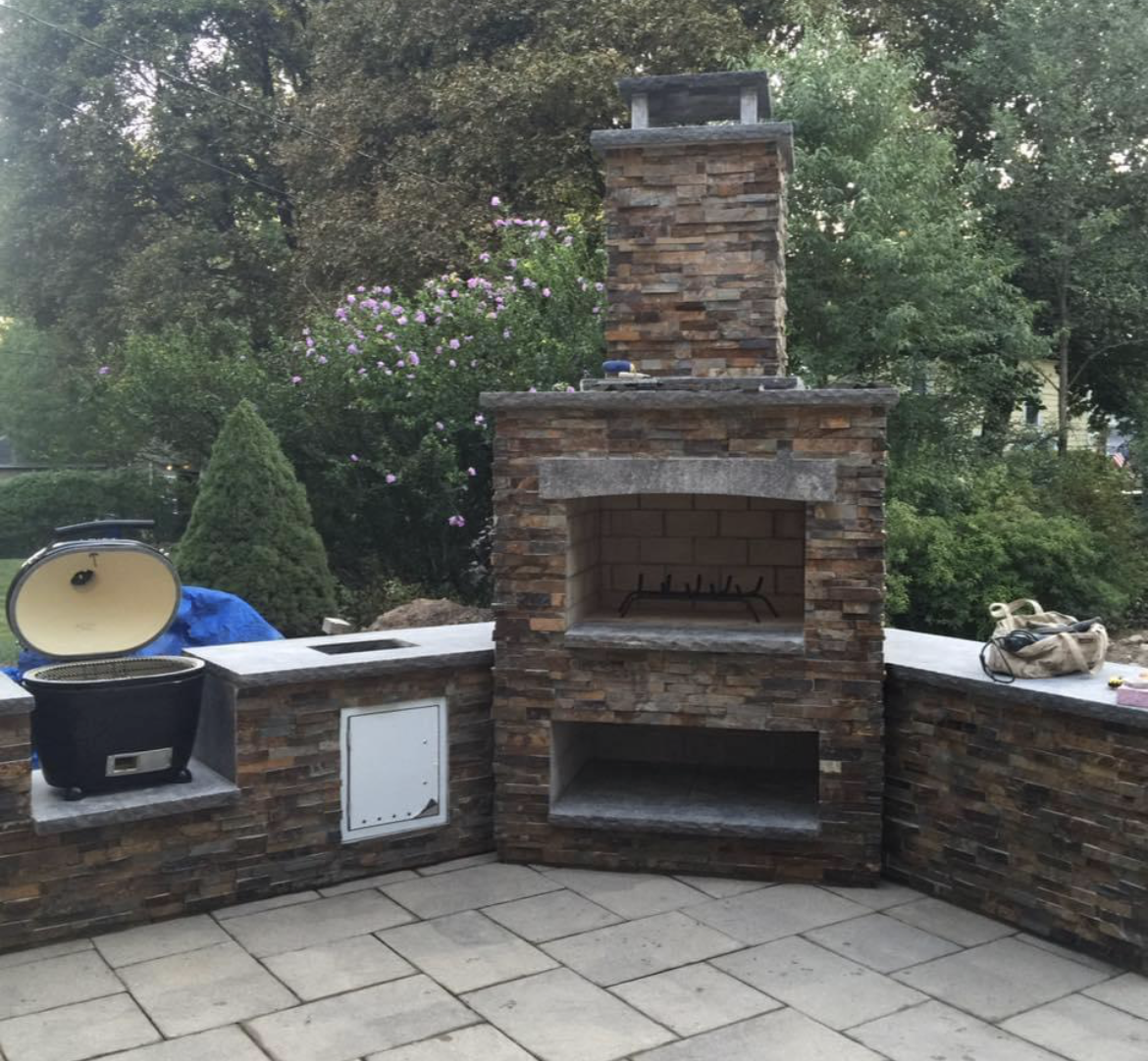 Patio with seating under a brown latticed pergola in a backyard with a white fence.