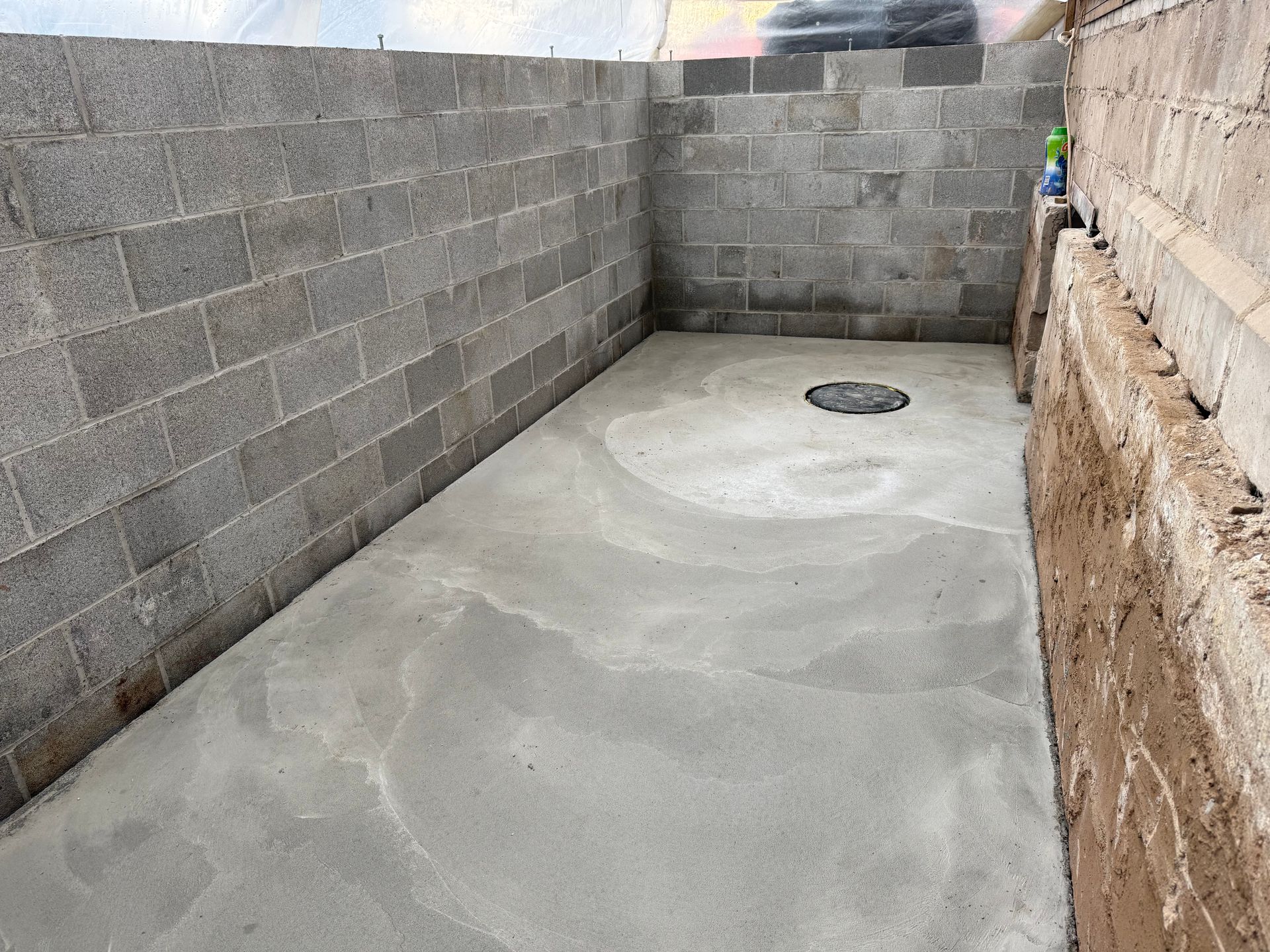 A small, rectangular outdoor enclosure with newly poured concrete flooring and grey concrete block walls.