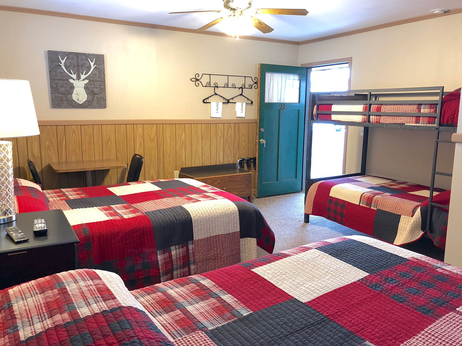 A motel room with three beds: two queen, one bunk bed, and rustic decor.