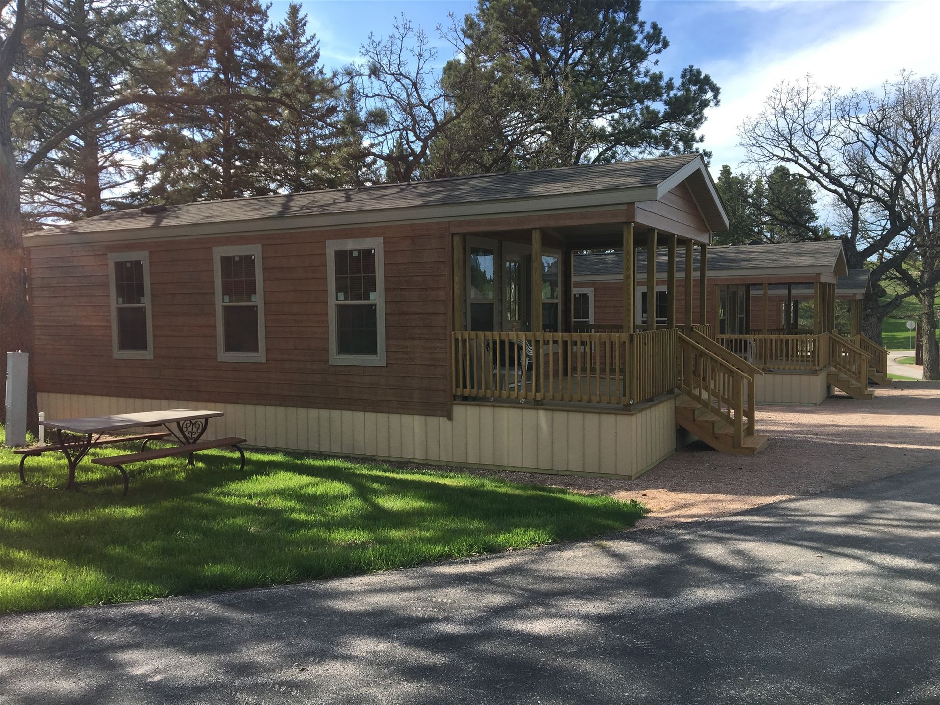 Brown cabins with porches, picnic table, and grassy area.