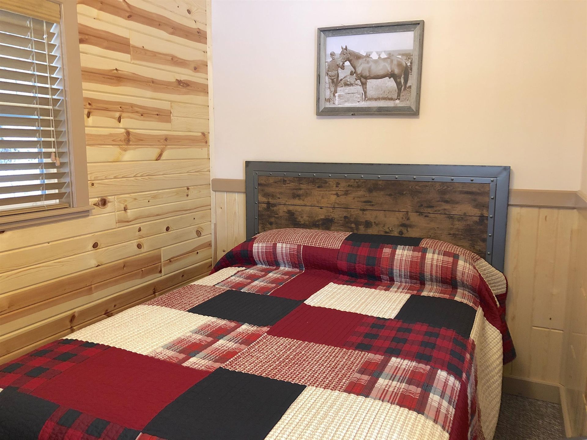 Bedroom with wooden paneling, patchwork quilt, and horse artwork.