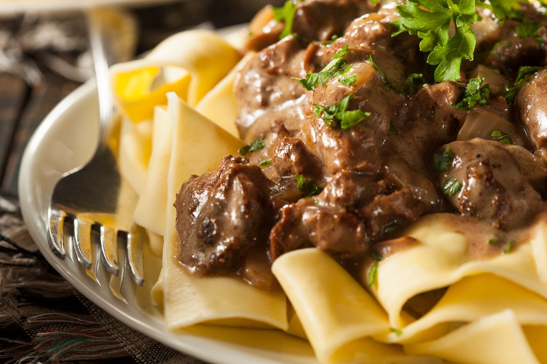 Beef stroganoff with egg noodles, garnished with parsley.