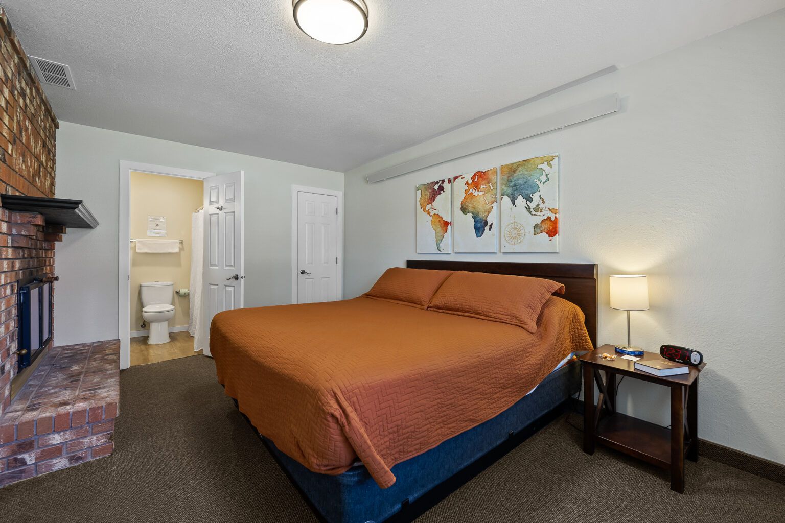 Bedroom with a double bed, world map art, fireplace, and attached bathroom.