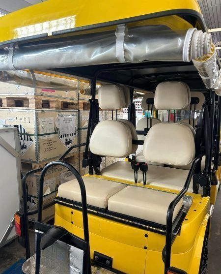 Un golf cart giallo con sedili bianchi è parcheggiato in un magazzino.